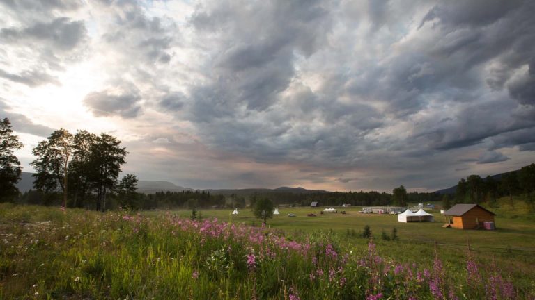 Blueberry River landscape. Grass fields surrounded by rolling hills and dark clouds in the sky.