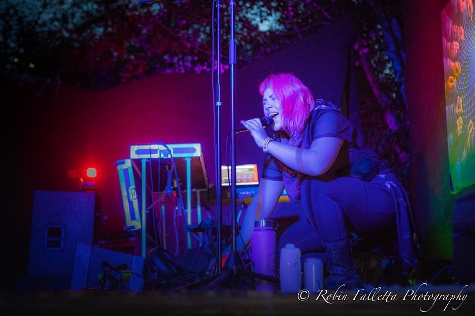 Ms.PAN!K crouches on stage singing into a microphone.