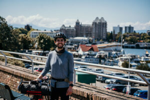Nick Avis stands with his bike in front of Victoria waterfront