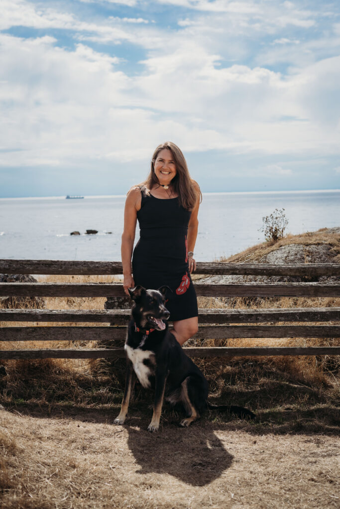 Danielle and her dog, Arlo, stand in front of the ocean 
